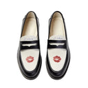 Pair of black loafers with red lipstick marks on a white background