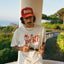 Man wearing a red 'Duke' cap and a white t-shirt with red text, standing outdoors.